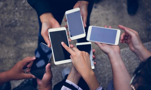 Five mobile phones held in the middle of a group